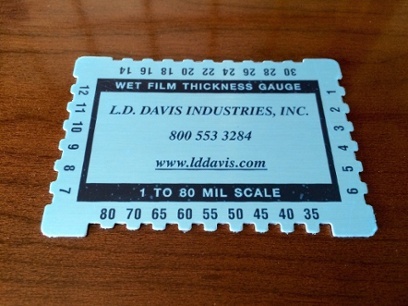 A Mil depth gauge lays on a wooden table with the LD Davis logo in the center